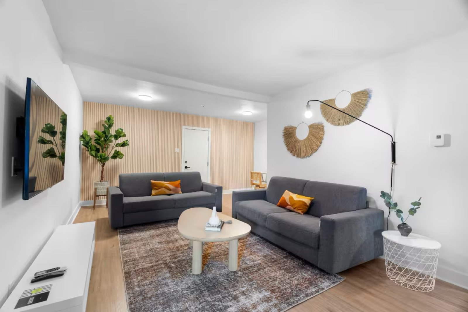 Salon meublé et lumineux avec deux canapés gris et un tapis