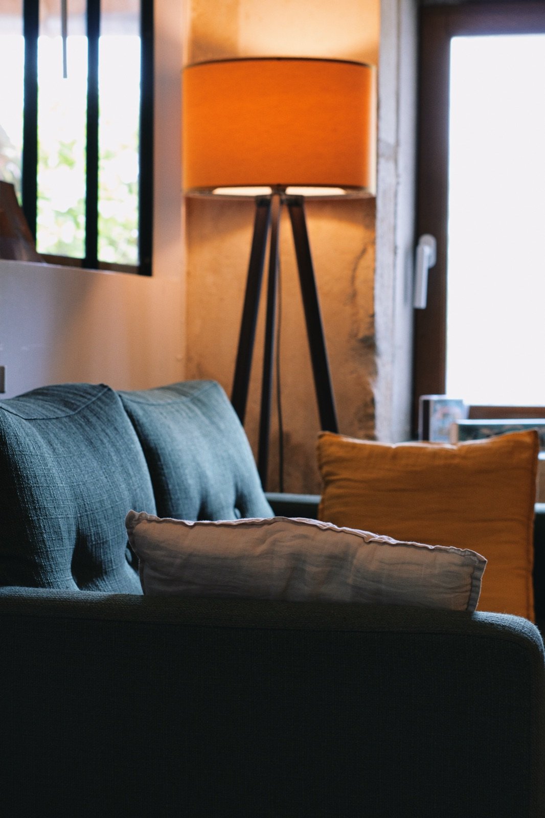 Lampe sur trépied orange et canapé bleu pétrole