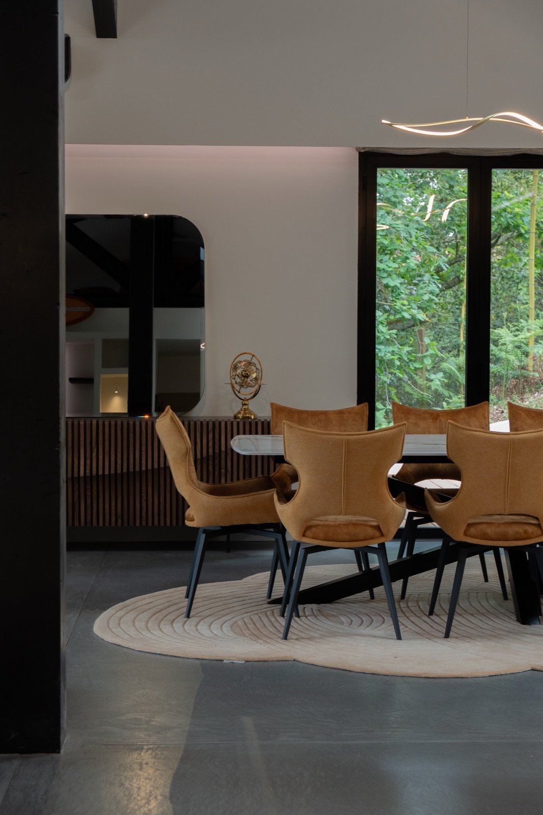Salle à manger avec chaises en bois et grande baie vitrée