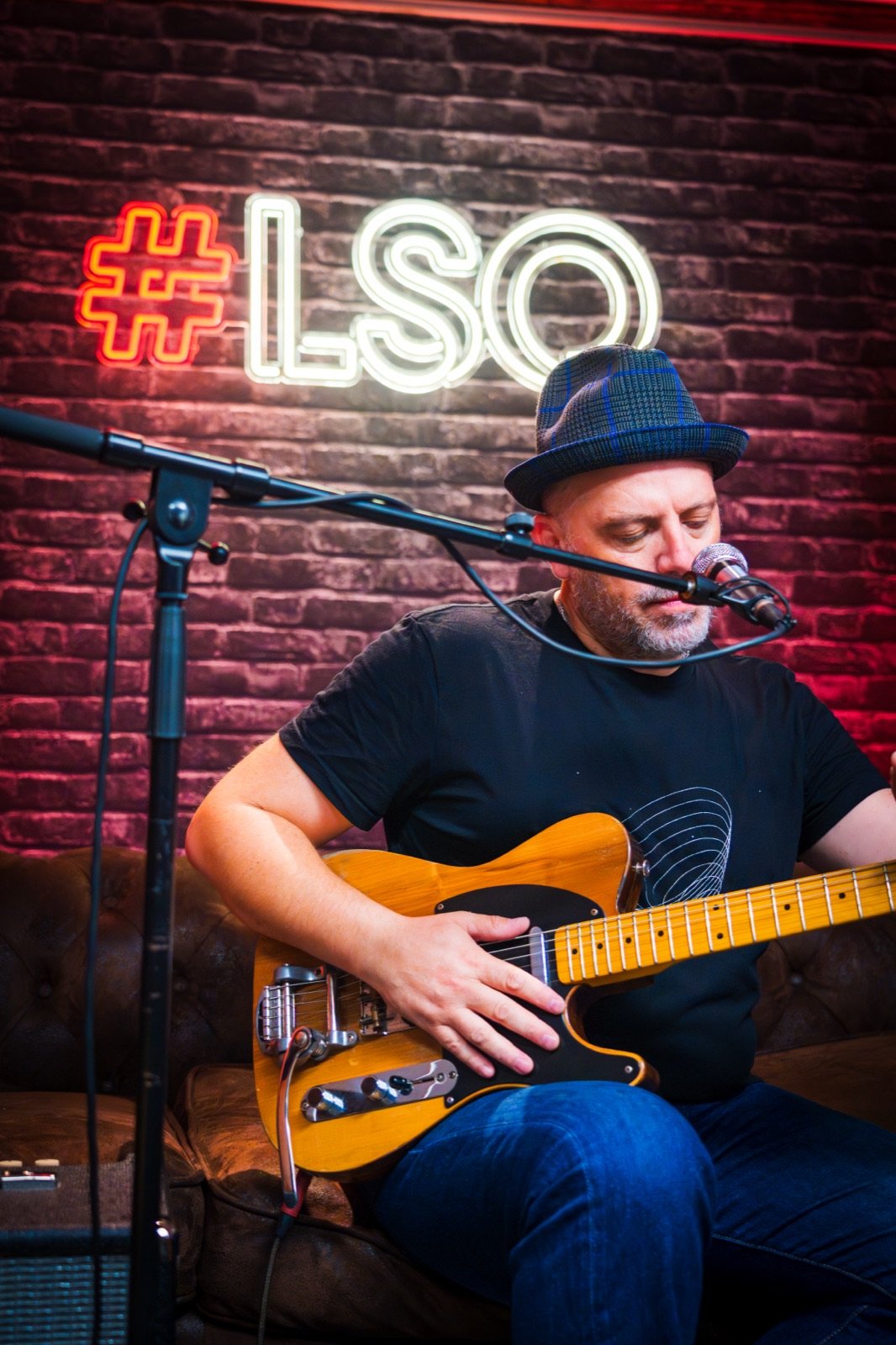 Musicien chantant et jouant de la guitare sous une enseigne néon