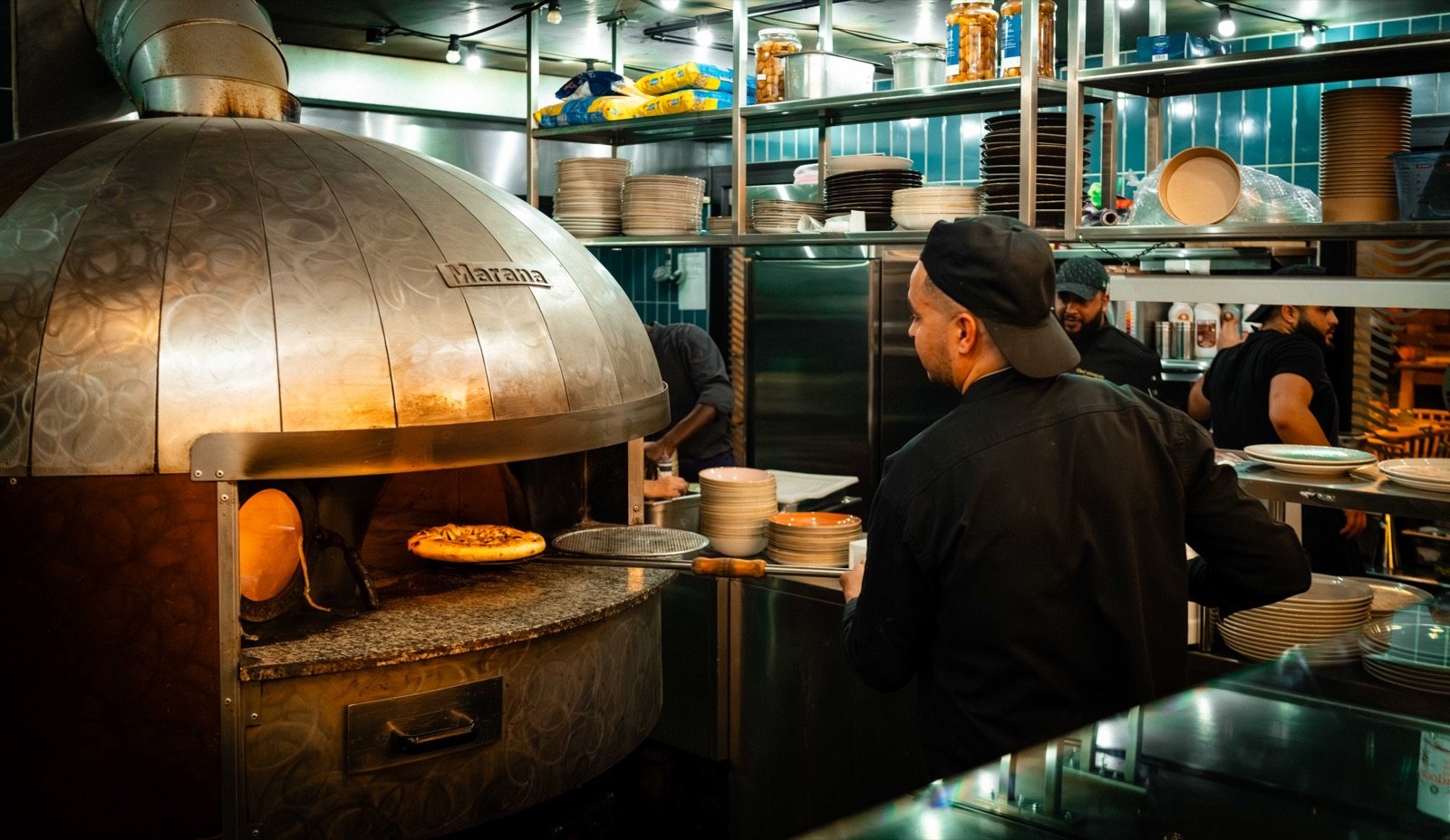 Cuisinier devant un four à pizza dans la cuisine d'un restaurant