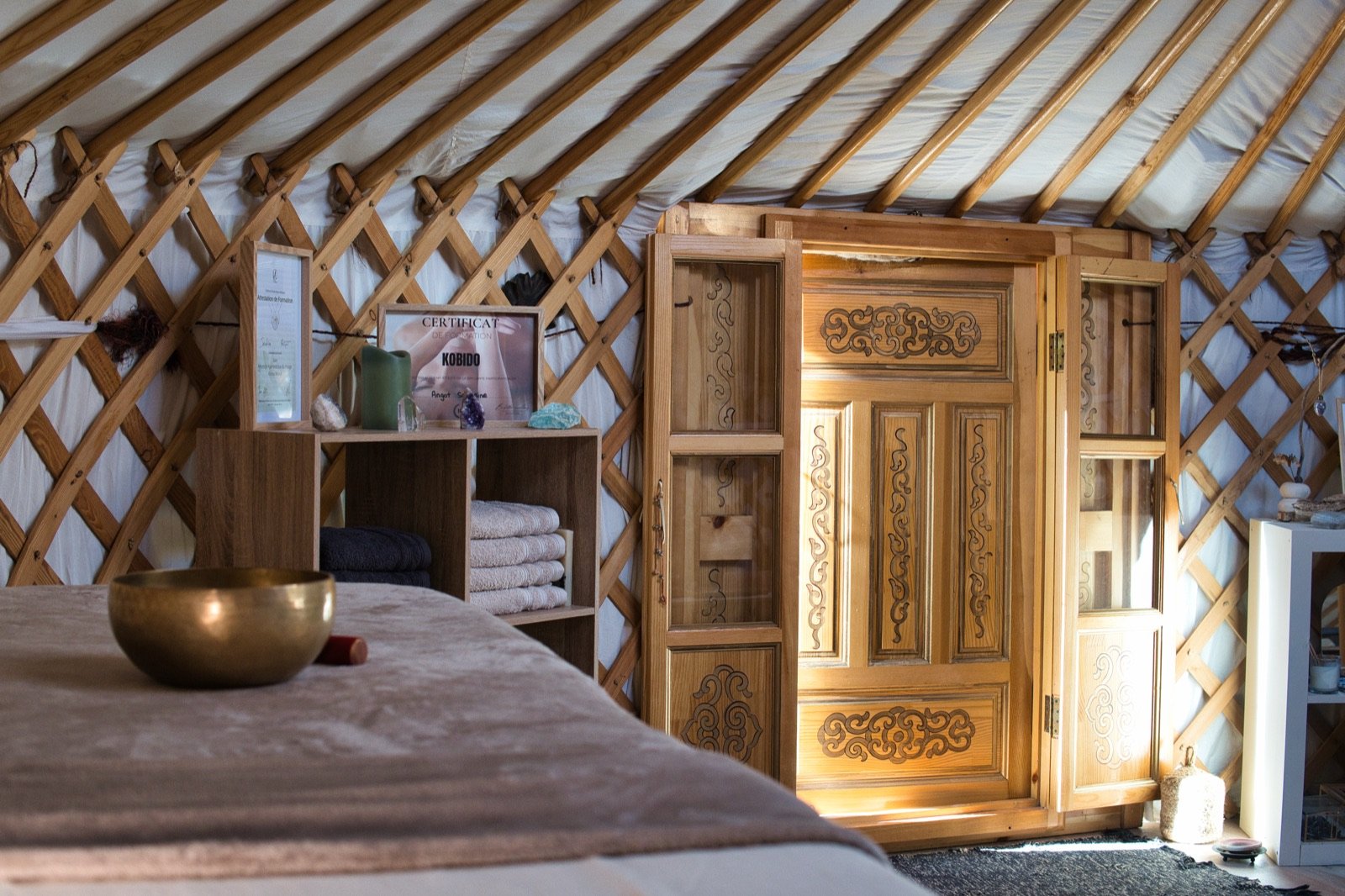 Intérieur de la yourte ORÂME : table de soin, armoire sculptée et bol chantant